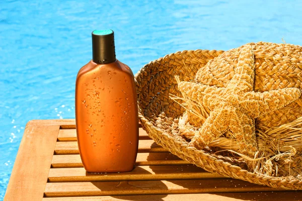 Λοσιόν μαυρίσματος με καπέλο ήλιο δίπλα στην πισίνα — Φωτογραφία Αρχείου