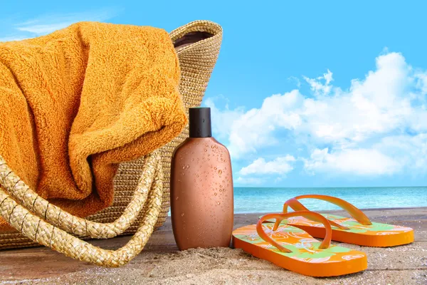 Loção bronzeada, com toalha na praia — Fotografia de Stock