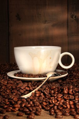 White coffee cup with spoon on roasted beans clipart