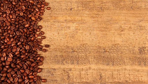 Жареные кофейные зерна на деревенском дереве — стоковое фото