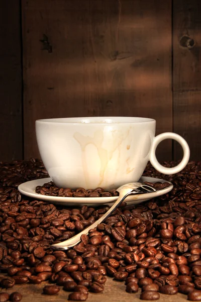 Witte koffiekopje met lepel op geroosterde bonen — Stockfoto
