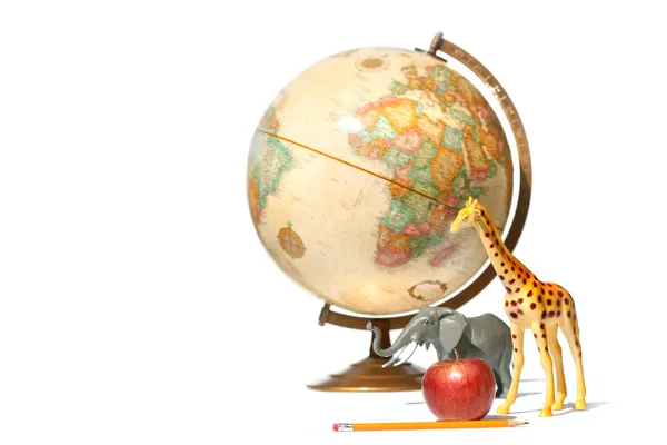 Глобус с игрушечными животными и яблоком на белом — стоковое фото