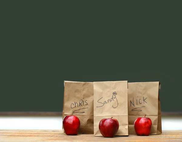 Lunch bags on desk with red apples — Stock Photo, Image