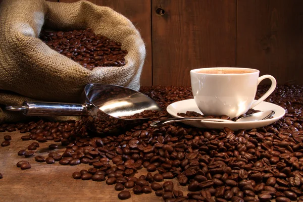 Šálek kávy s jutovým pytlem pražených bobů Stock Snímky
