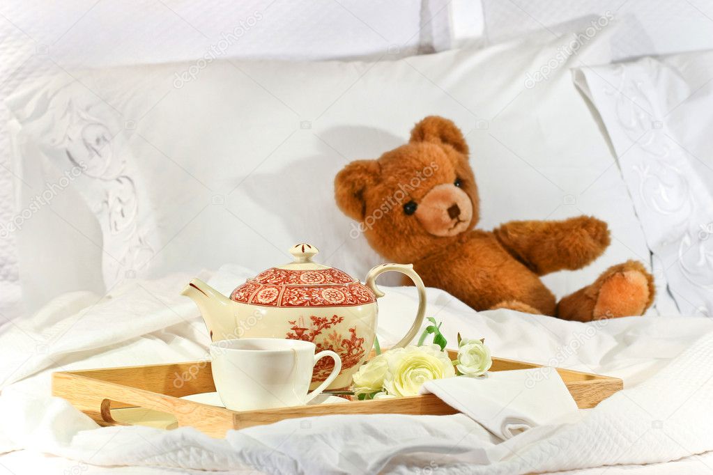 Tea in bed with teddy on white sheets