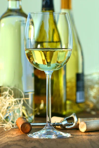 Copa de vino blanco con botellas sobre mesa de roble —  Fotos de Stock