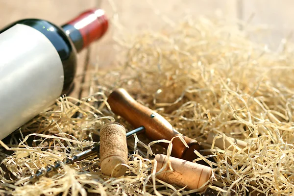 Botella de vino tinto con sacacorchos y paja de embalaje — Foto de Stock