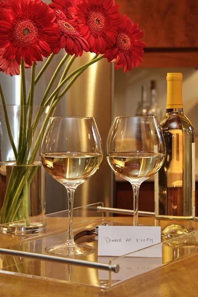 Glasses of white wine with gerbera daisies on counter in the kitchen — Stock Photo, Image