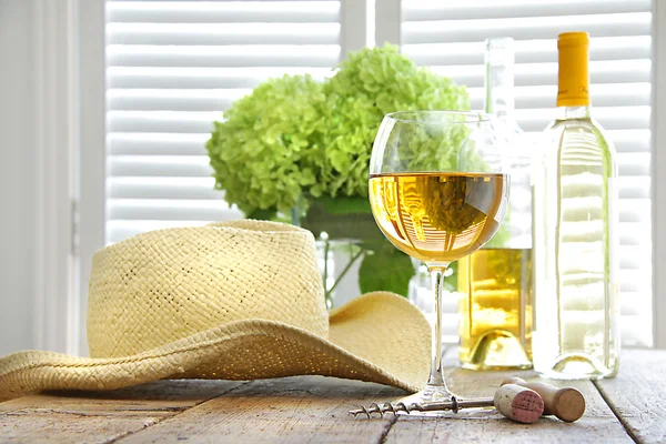 Ποτήρι κρασί με ψάθινο καπέλο στο τραπέζι — Φωτογραφία Αρχείου