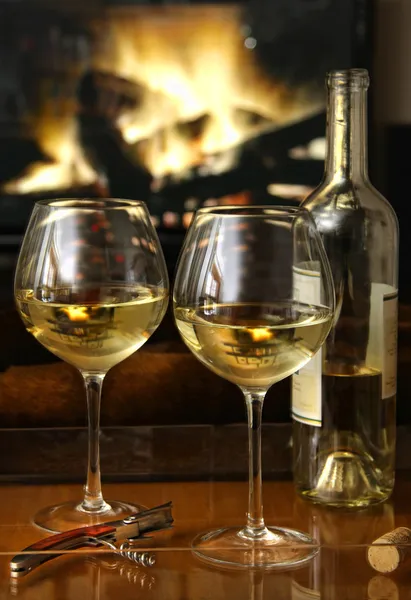 Απολαμβάνοντας ποτήρια λευκό κρασί μπροστά από μια θερμή πυρκαγιά — Φωτογραφία Αρχείου