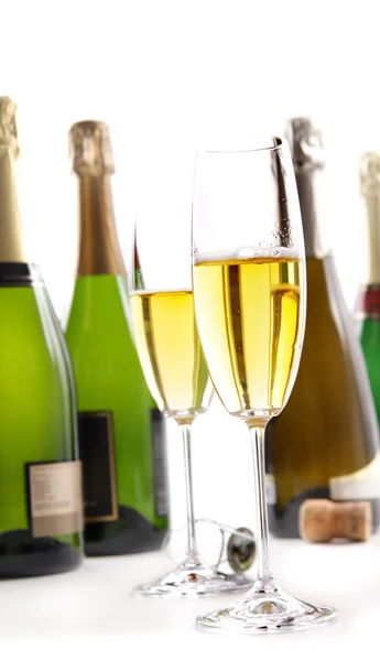 Glazen champagne met flessen op wit — Stockfoto