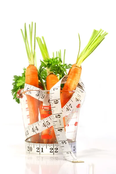 Zanahorias en una taza de medir con cinta métrica —  Fotos de Stock