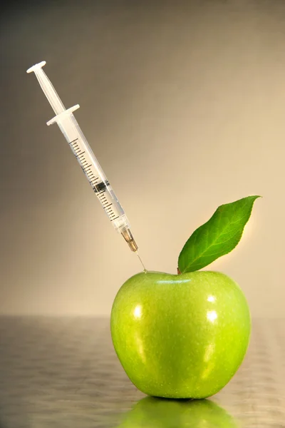 Close-up of syringe in green apple — Stock Photo, Image