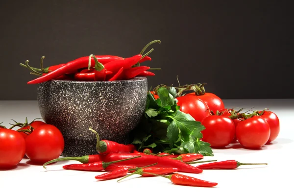 Peperoni rossi e pomodori con ciotola di ganite al buio — Foto Stock