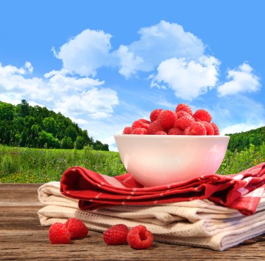 Bowl of raspberries on rustic table clipart