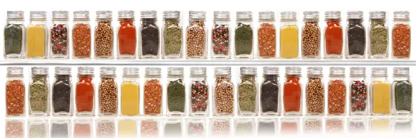 Assorted spices on two layer shelves against white — Stock Photo, Image