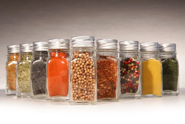 Bottles of colorful spices with grey — Stock Photo, Image