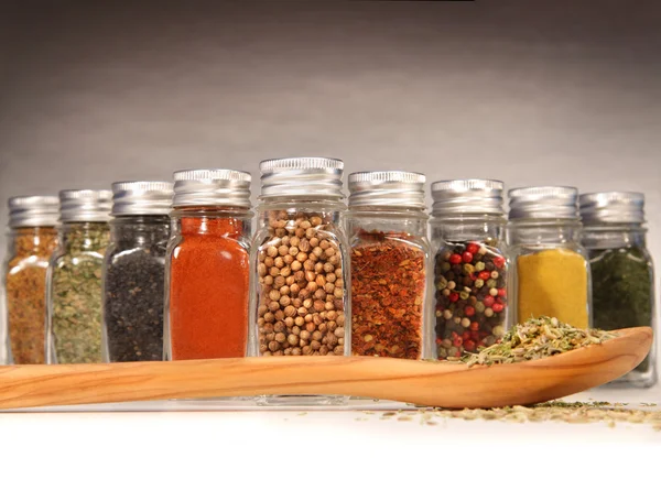 Spices in bottles with wooden spoon — Stock Photo, Image