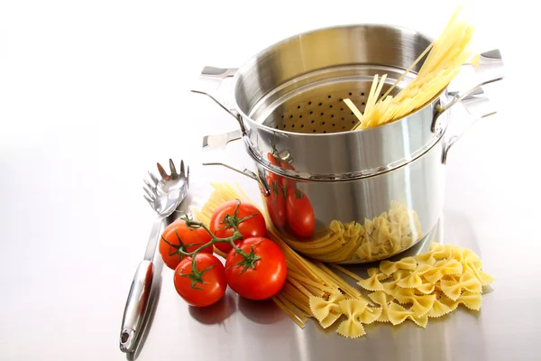 Kookpot met ongekookte pasta en tomaten — Stockfoto