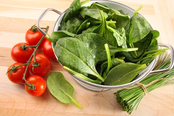 Colador con hojas de espinaca y tomates —  Fotos de Stock