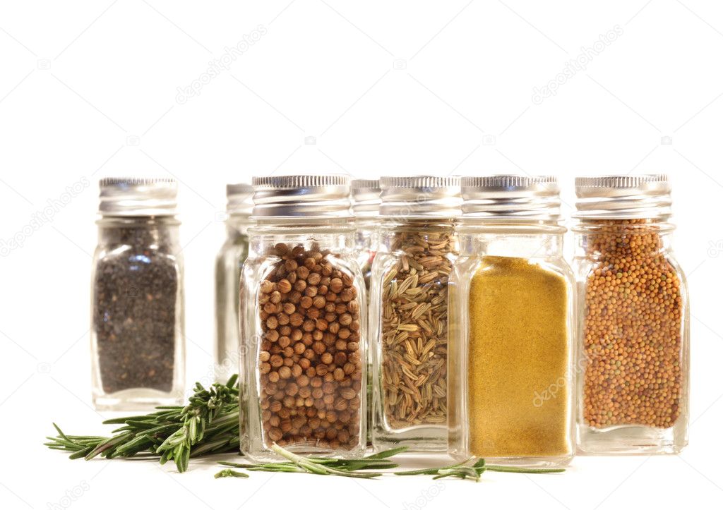 Spice jars with fresh rosmary leaves against white