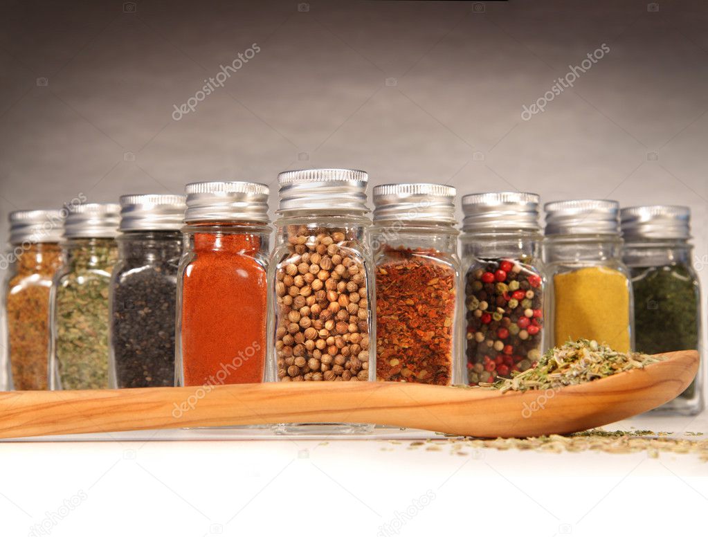 Spices in bottles with wooden spoon