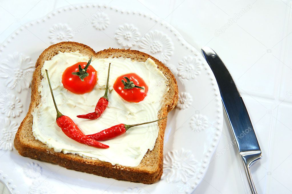 Food arranged into a smiley face on sandwich