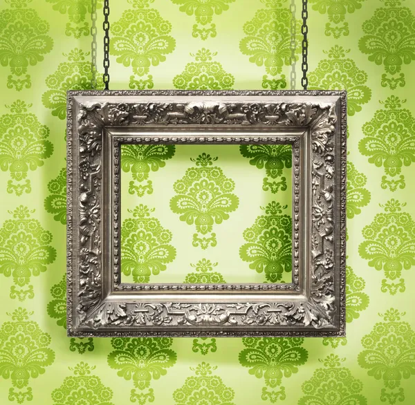 Marco de imagen de plata colgado contra fondo de pantalla floral —  Fotos de Stock