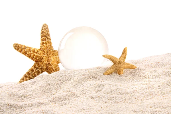 Křišťálová koule s hvězdicemi v písku — Stock fotografie