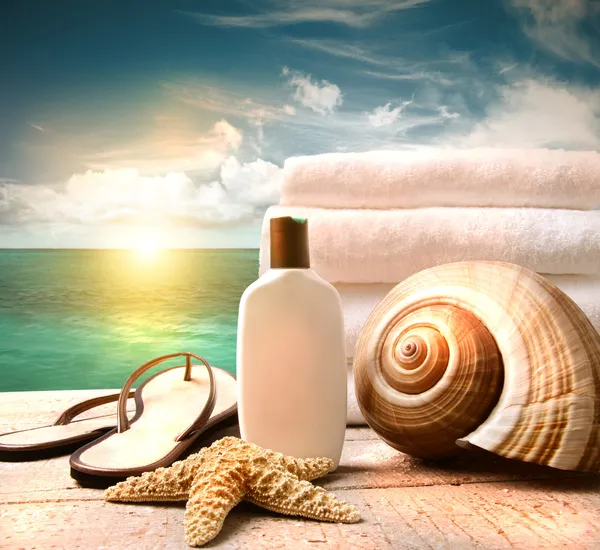 Sunblock lotion and towels and ocean scene Stock Photo