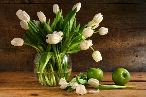 Белые тюльпаны в стеклянной вазе на деревенском дереве — стоковое фото