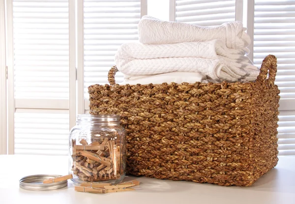 Tvättkorg med sängkläder på bord — Stockfoto