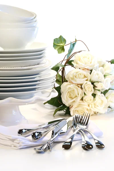 Placas brancas empilhadas com utensílios e rosas — Fotografia de Stock