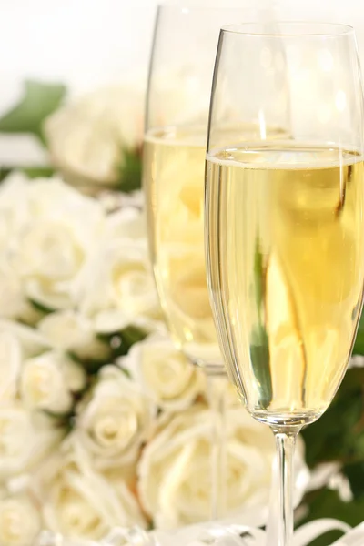 Close-up of champagne glasses with a bouquet of roses — Stock Photo, Image
