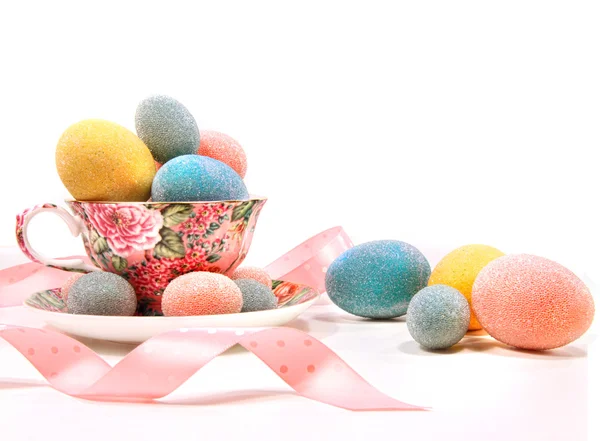 Brightly colored eggs in tea cup on white — Stock Photo, Image