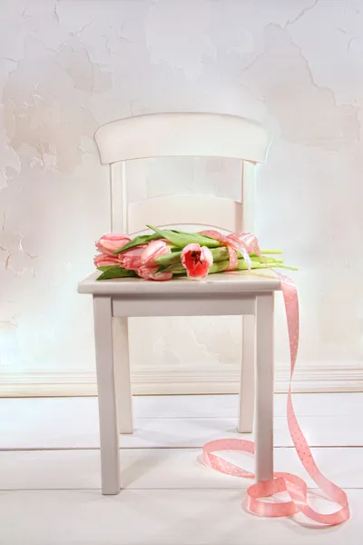 Kleiner weißer Stuhl mit rosa Tulpen — Stockfoto