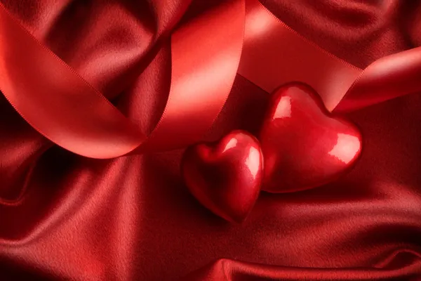 Zwei rote Herzen mit Schleife auf Satin — Stockfoto