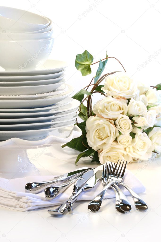 White plates stacked with utencils and roses