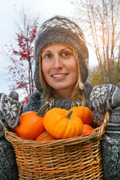 Young woman holding a basket full of pumpkins — Stock Photo, Image