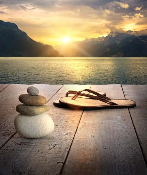 Visa sandaler och stenar på dock vid solnedgången — Stockfoto