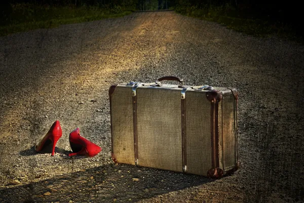 Régi bőrönd piros cipővel az úton — Stock Fotó