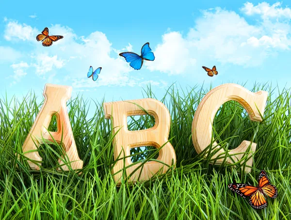 Lettres ABC dans l'herbe avec des papillons Images De Stock Libres De Droits
