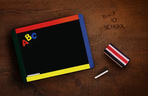 Van het kind schoolbord met gum op oude bureau — Stockfoto