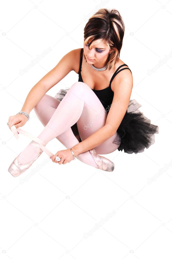 A young ballerina tying her ballet slippers.