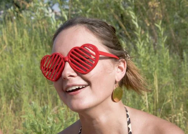 Chica sonriendo en gafas de sol rojas - corazones . —  Fotos de Stock