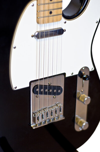 Classic electric guitar. Fragment of a white background. Selective focus on the strings. Blur.