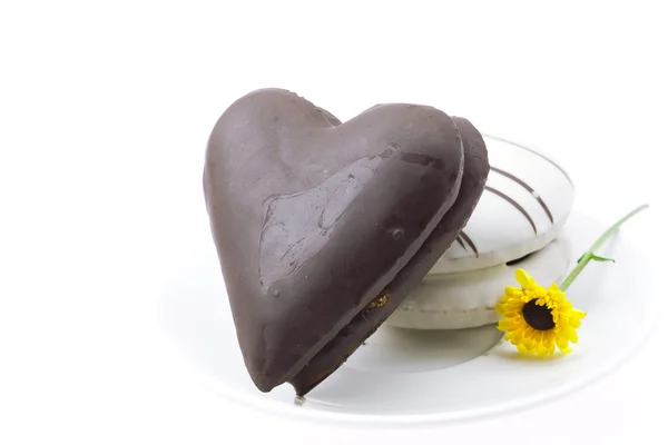 Ciasto w formie serca i kwiat na płytce na białym tle — Zdjęcie stockowe