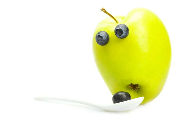 Joke apple with eyes and a spoon with blueberries isolated on wh — Stock Photo, Image