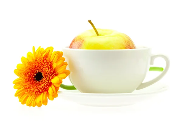 Μήλο σε ένα κύπελλο και ένα λουλούδι που απομονώνονται σε λευκό — Φωτογραφία Αρχείου