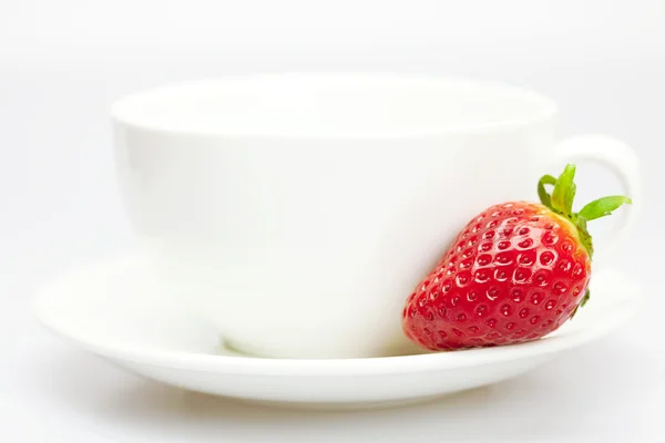 Morangos suculentos e uma xícara de branco isolado em branco — Fotografia de Stock